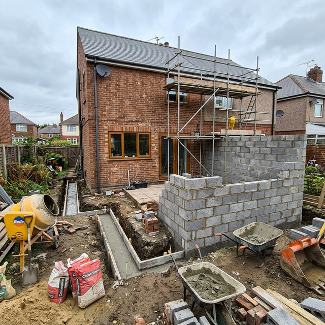 UK house extension under construction with foundation trenches near drainage